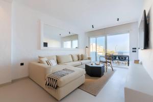 a white living room with a couch and a table at Villas Flamenco Beach Conil in Conil de la Frontera