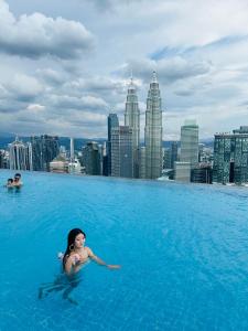 a woman swimming in a pool on the roof of a building at Platinum Suites KLCC SKY WORLD in Kuala Lumpur