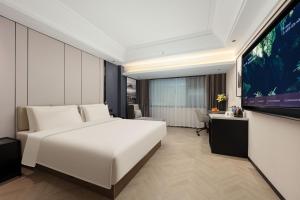 a bedroom with a white bed and a flat screen tv at Atour X Hotel Xiamen Exhibition Center Gudishi Station in Xiamen