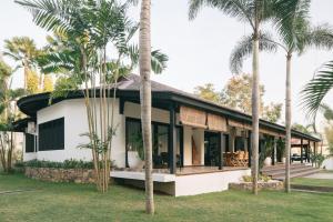 a house with palm trees in front of it at Villa Puri Greenlot Cemagi in Canggu