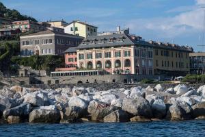 a group of buildings with rocks in front of the water at Grand Hotel Portovenere in Portovenere