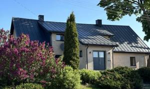 a house with a black roof and some bushes at Akmerenta - Kadagių dvarelis in Akmenė