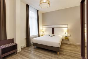 a bedroom with a bed and a large window at Grand Hôtel Lille in Lille