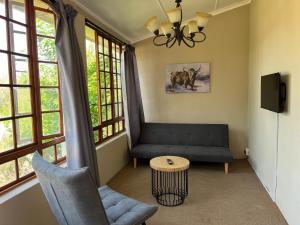 a living room with a couch and a table and windows at Lindela House in Kokstad