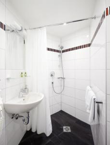 La salle de bains blanche est pourvue d'un lavabo et d'une douche. dans l'établissement Central Hotel Garni, à Wurtzbourg