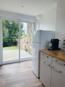 a kitchen with a refrigerator and a sliding glass door at Charmante Maison l Jardin l Clim in Carbes