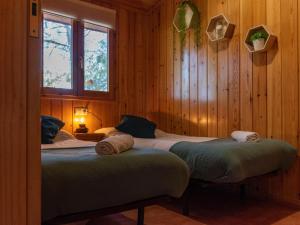two beds in a room with wooden walls at Las Casitas del Pinar in Bayubas de Abajo