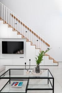 a living room with a glass coffee table and a staircase at Calliope luxury loft with backyard in Ierápetra