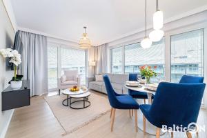a living room with a dining table and blue chairs at Apartamenty BalticON Polanki Aqua in Kołobrzeg