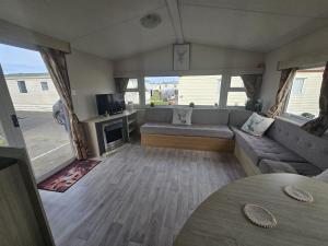 a living room with a couch and a tv at Ruby a modern caravan in Rhyl in Rhyl
