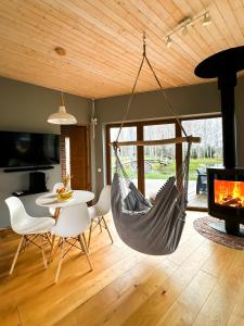 a hammock in a living room with a table and a fireplace at Dabas Osta in Jūdaži