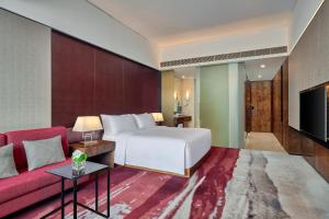 a hotel room with a bed and a red couch at Hilton Guangzhou Tianhe in Guangzhou