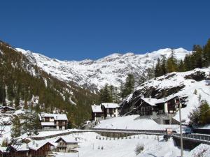 a snow covered mountain with houses and a train station at Il Piccolo Residence in Gressoney-la-Trinité