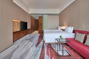 a hotel room with a bed and a red couch at Hilton Guangzhou Tianhe in Guangzhou