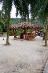 a pavilion with a straw roof on a beach with palm trees at Khaolak Banana Bungalow in Khao Lak