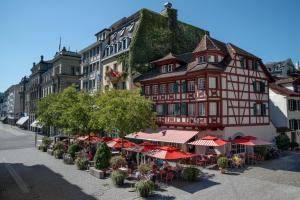 a building with tables and umbrellas in front of it at Hotel Rebstock in Luzern