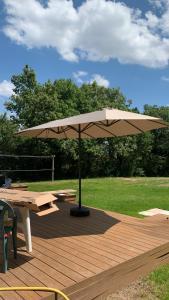 a picnic table and an umbrella on a wooden deck at Belle maison 6 personnes à 2min du Lac du Jaunay, et 15min des plages Vendéennes in La Chapelle-Hermier