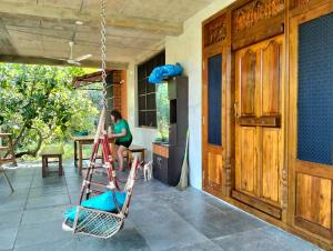 a woman sitting on a ladder on a porch at Ashoksfarm in Auroville