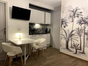a kitchen with a table and chairs with palm trees on the wall at Eden urbain au centre ville in Chalon-sur-Saône