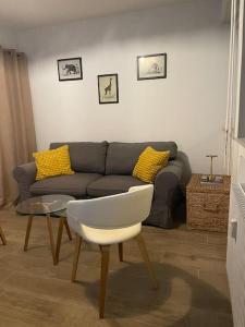 a living room with a couch and a white chair at Eden urbain au centre ville in Chalon-sur-Saône +4 photos