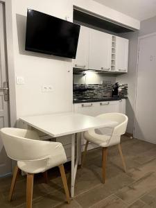 a kitchen with a white table and two white chairs at Eden urbain au centre ville in Chalon-sur-Saône