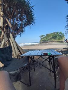 ein Picknicktisch und ein Stuhl neben einem Strand in der Unterkunft Tenda camping in Madasari