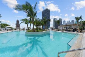 a large swimming pool with palm trees in a city at La Terrasse by VIAC - Luxury Bay View Studio with Balcony 29th Floor Miami in Miami