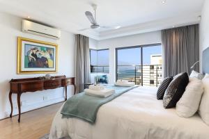 Un dormitorio con una gran cama blanca con ventana. en Ocean View Properties - Penthouse, en Ciudad del Cabo