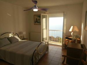 - une chambre avec un lit, un ventilateur de plafond et une fenêtre dans l'établissement Villa Saint-Michel, à Galéria