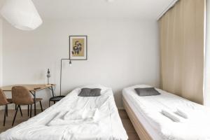 two beds in a room with a table at Kotimaailma Apartments Pukkila - New studio for 2 in Turku