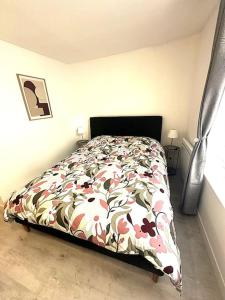 ein Schlafzimmer mit einem Bett mit geblümter Tagesdecke in der Unterkunft Résidence Champenoise 3, Troyes - France in Troyes