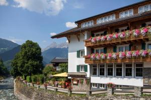 a building with flowers on the balconies next to a river at Apparthotel Litz in Schruns