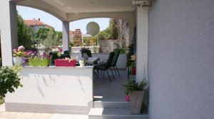 un patio al aire libre con sillas y una mesa con flores en Apartments Nika, en Zadar