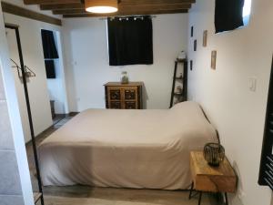 a bedroom with a white bed and a wooden table at Maison pour 4 personnes in Lesperon
