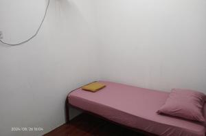 a small bed in a room with a yellow towel on it at NR Guest House in Kangar