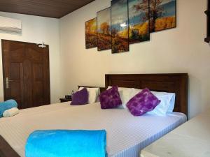 a bedroom with a large bed with purple pillows at Dinu Lanka Resort in Katunayaka