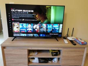 een flatscreen-tv bovenop een entertainmentcentrum bij GardenHouse in Athene +4 foto's