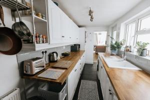 a kitchen with white cabinets and a wooden counter top at SUN COTTAGE - Cosy Cottage in Ulverston with a log burner in Ulverston, Cumbria in Ulverston