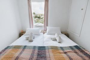 a bedroom with two beds with pillows and a window at SUN COTTAGE - Cosy Cottage in Ulverston with a log burner in Ulverston, Cumbria in Ulverston