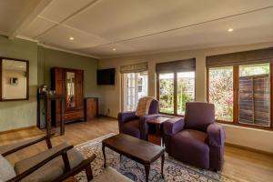 un soggiorno con un divano, sedie e un tavolo di Glen Eden Lodge a Lidgetton