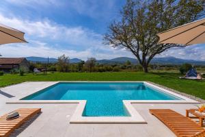 a swimming pool in a backyard with chairs and an umbrella at 2-bedroom Villa Providenca in Bajagić