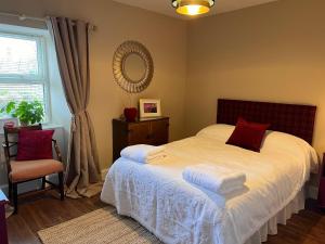a bedroom with a bed with white sheets and red pillows at Berry View - Idyllic cosy cottage on berry farm in Blairgowrie