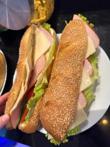a sandwich on a plate with a person holding it at Villa White in Ksamil