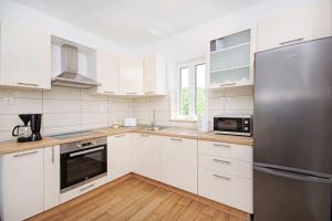a kitchen with white cabinets and a stainless steel refrigerator at House Tonko in Postira