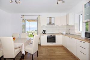 a kitchen with white cabinets and a table with chairs at House Tonko in Postira