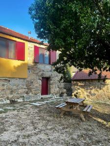 a picnic table in front of a stone building with a red door at Nascente, place in nature next to a waterfall in Loureiro +24 photos