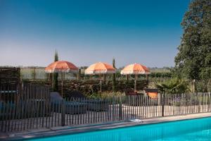 a fence with umbrellas and chairs and a pool at Villa met privézwembad, 10 minuten van het strand in Noordwelle