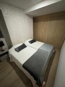 a bedroom with a bed with white sheets and black pillows at Unidad recidencial San basilio in Sabaneta