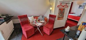 a small room with a table and red chairs at Auf dem alten Deich in Sande