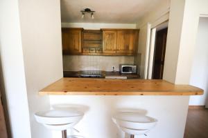 a kitchen with wooden cabinets and a counter with two stools at Chalet Alpina résidence Val Claret in Tignes